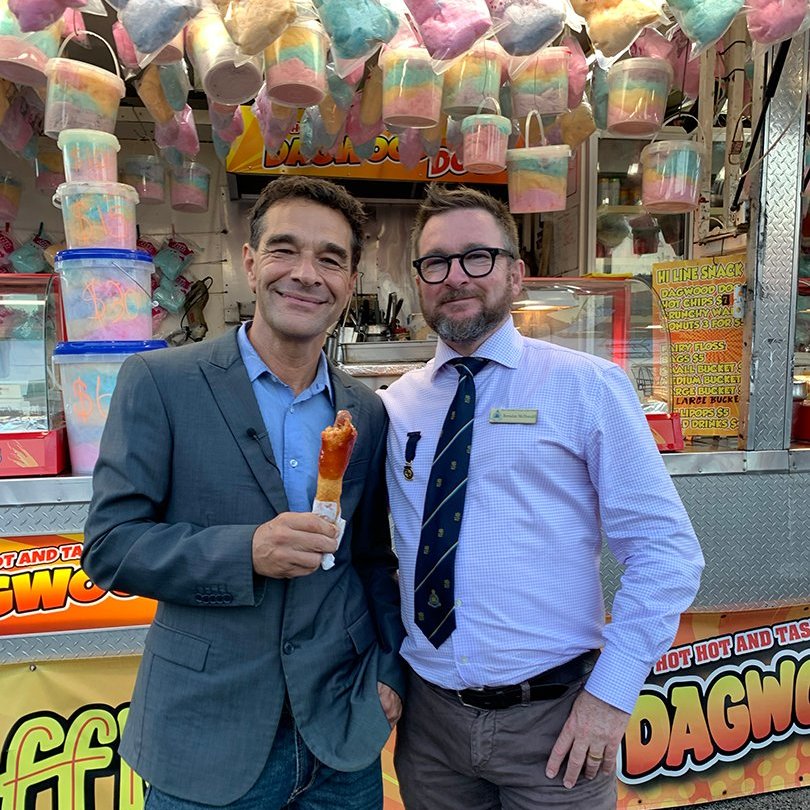 Brendan and a Channel 7 representative stand together in front of a cotton candy stall.