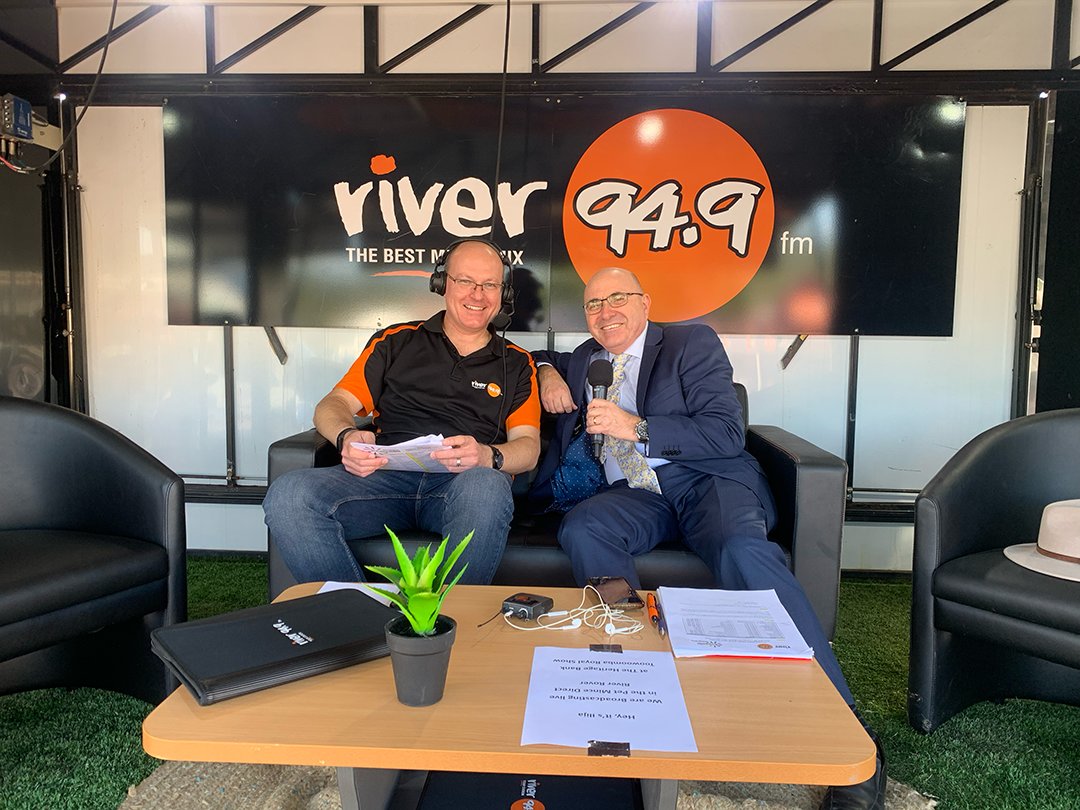 Two River 949 hosts sit together on a couch in front of a River 949 Sign. They are broadcasting live at the Toowoomba Royal Show.