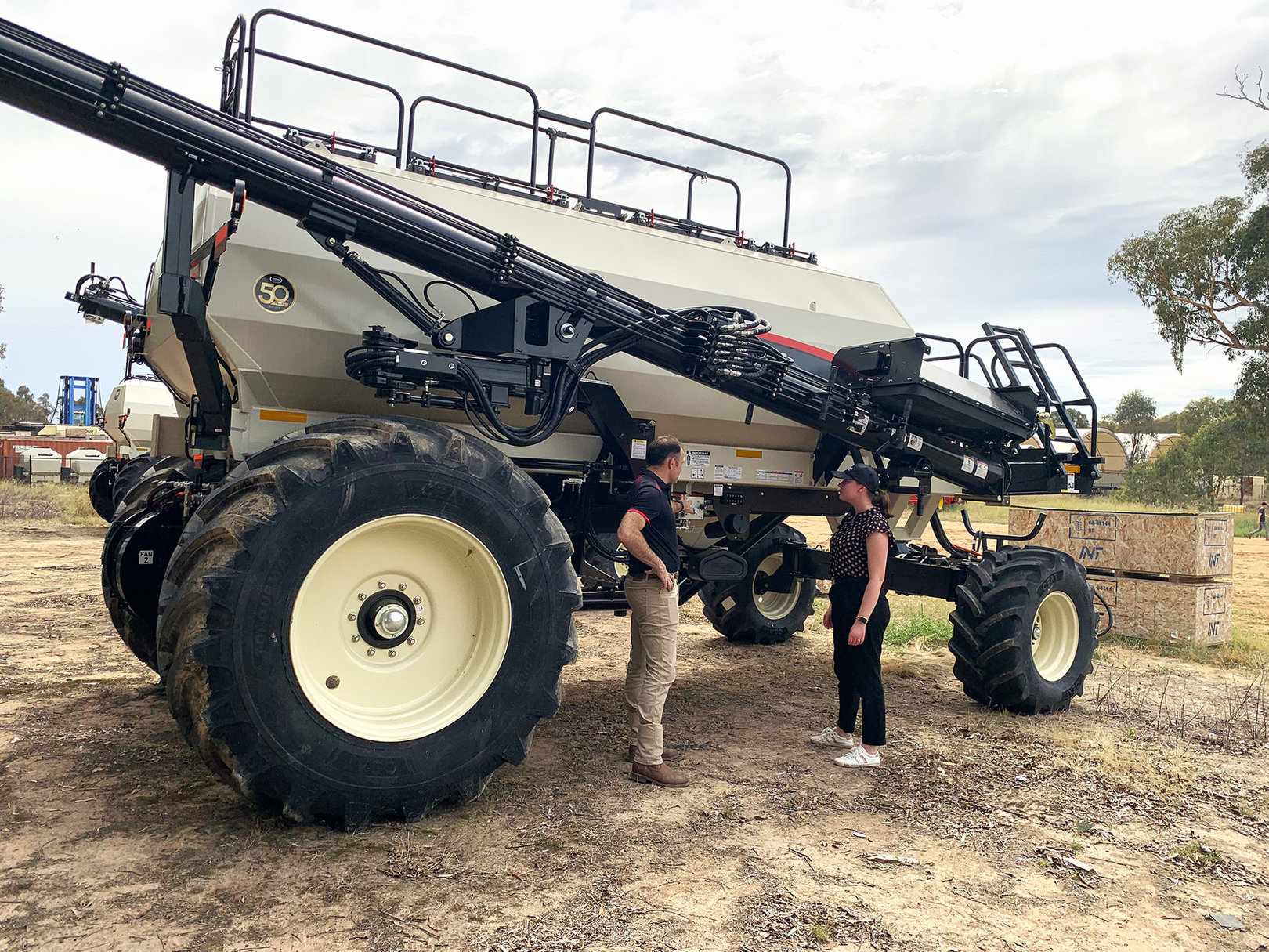 Two people stand in front of a Bourgault Air Cart. One of them is explaining the features to the other person.