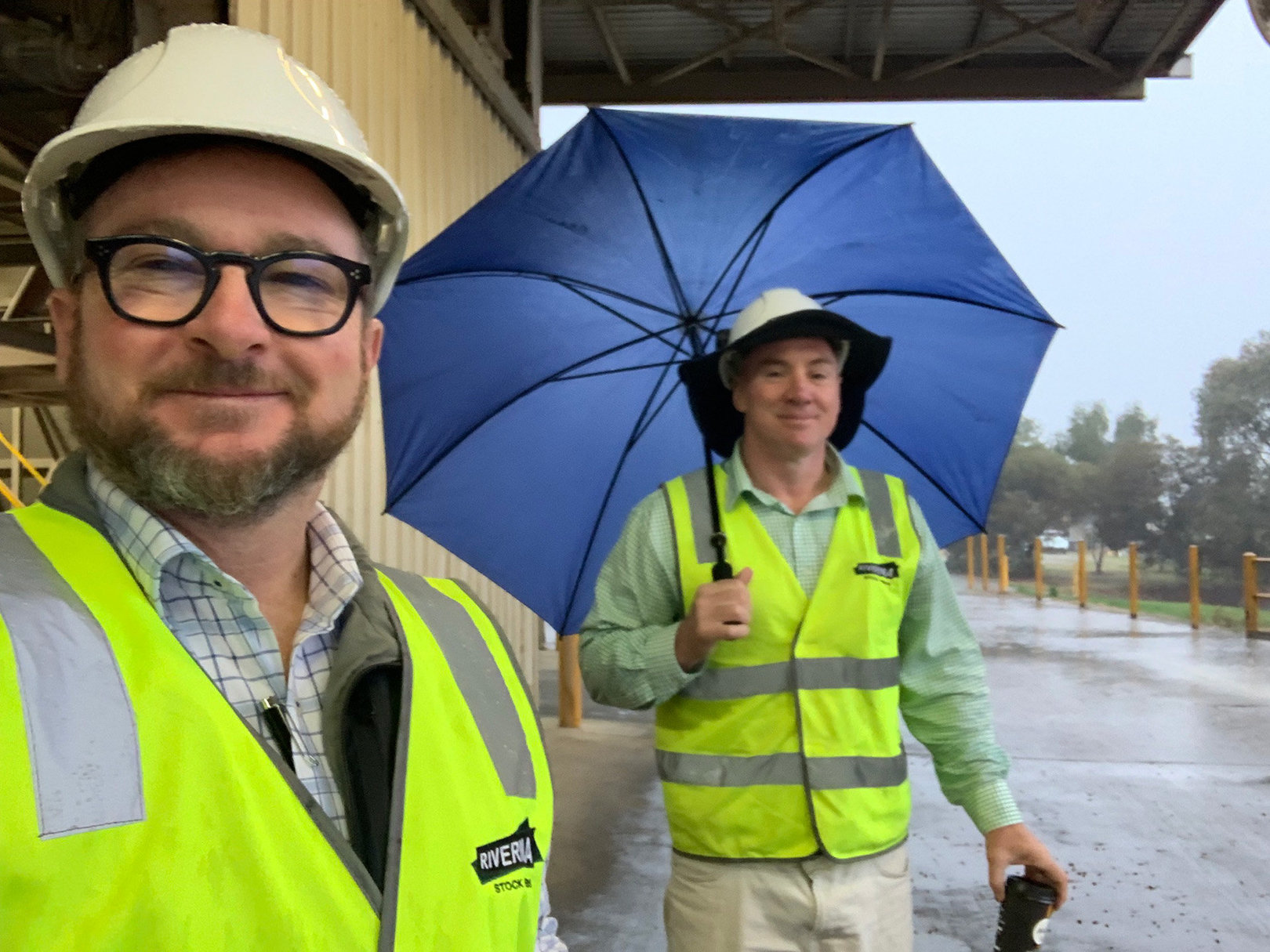 Brendan and Nick Hall from Riverina Stockfeeds take a selfie together, each wearing yellow high-viz vests and safety hats.