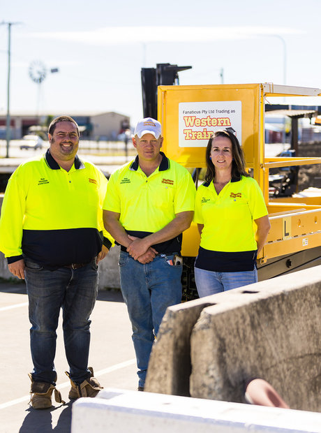 Three Western Trainers trainers stand together in front of a scissor lift