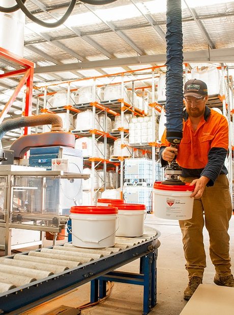 A man is filling buckets in a factory.