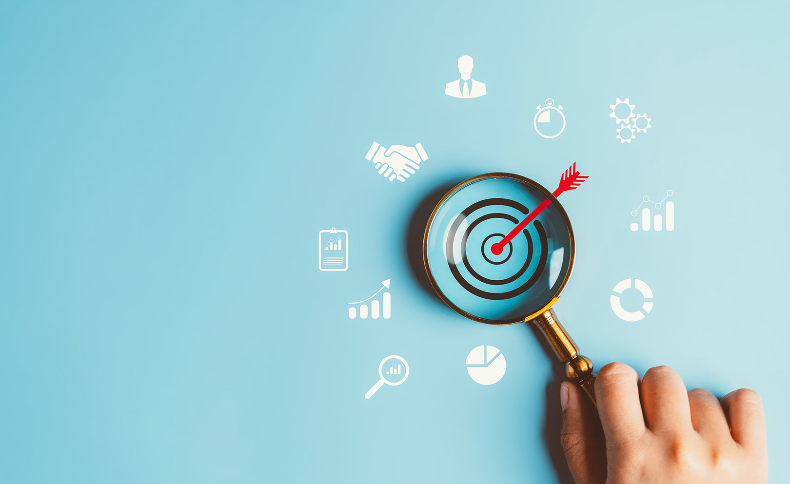 Magnifying glass focused on illustrated target. Business icons surround magnifying glass