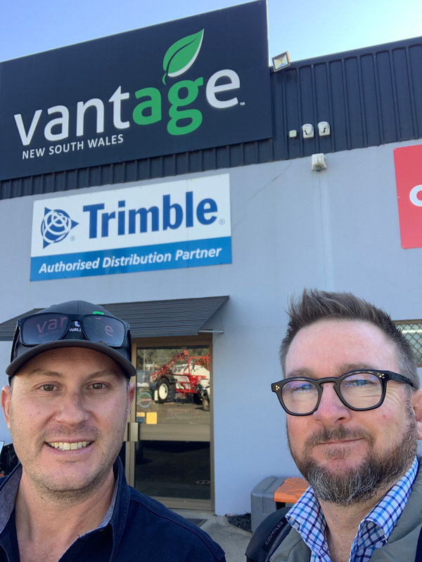 Brendan and Mick Casey of Vantage NSW take a selfie together in front of the Vantage storefront. Below the Vantage sign is the Trimble sign.