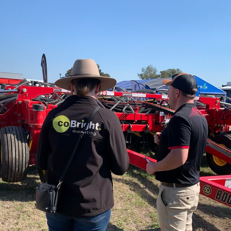 Caitlin wears a CoBright branded jacket while she talks to a Borugault team member. They are looking at Bourgault's 3820 ParaLink Coulter Drill