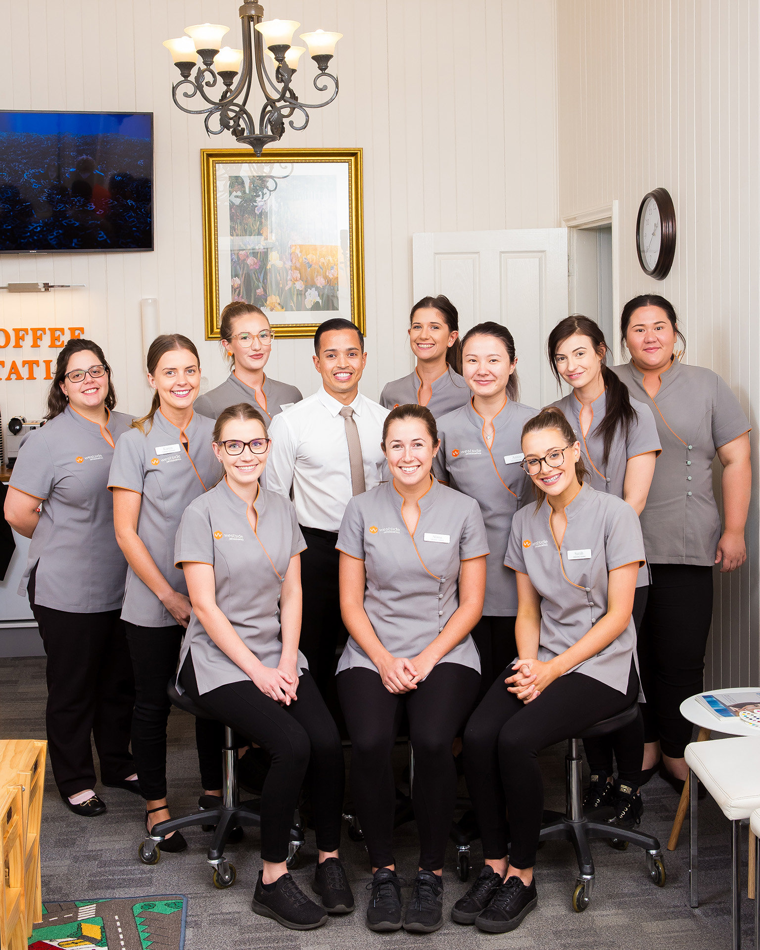 Westside Orthodontics team in their waiting room. The space is decorated with framed art