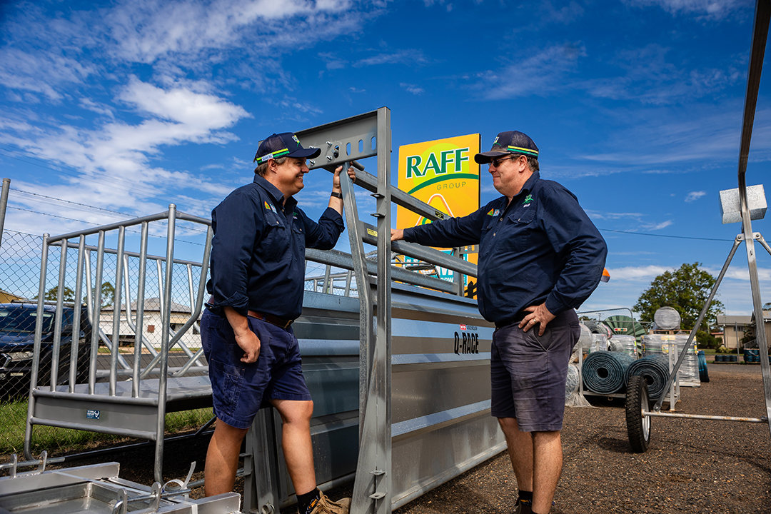 Two RAFF Group team members are talking in front of a cattle crush in a RAFF Group product yard.