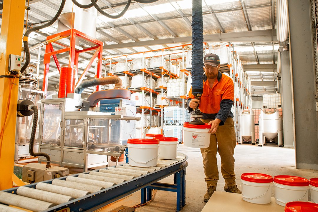 A man is filling buckets in a factory.